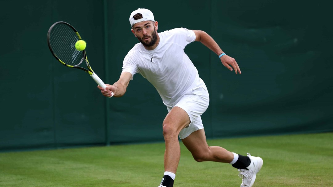 Jacob Fearnley reaching to hit a forehand on court at Wimbledon