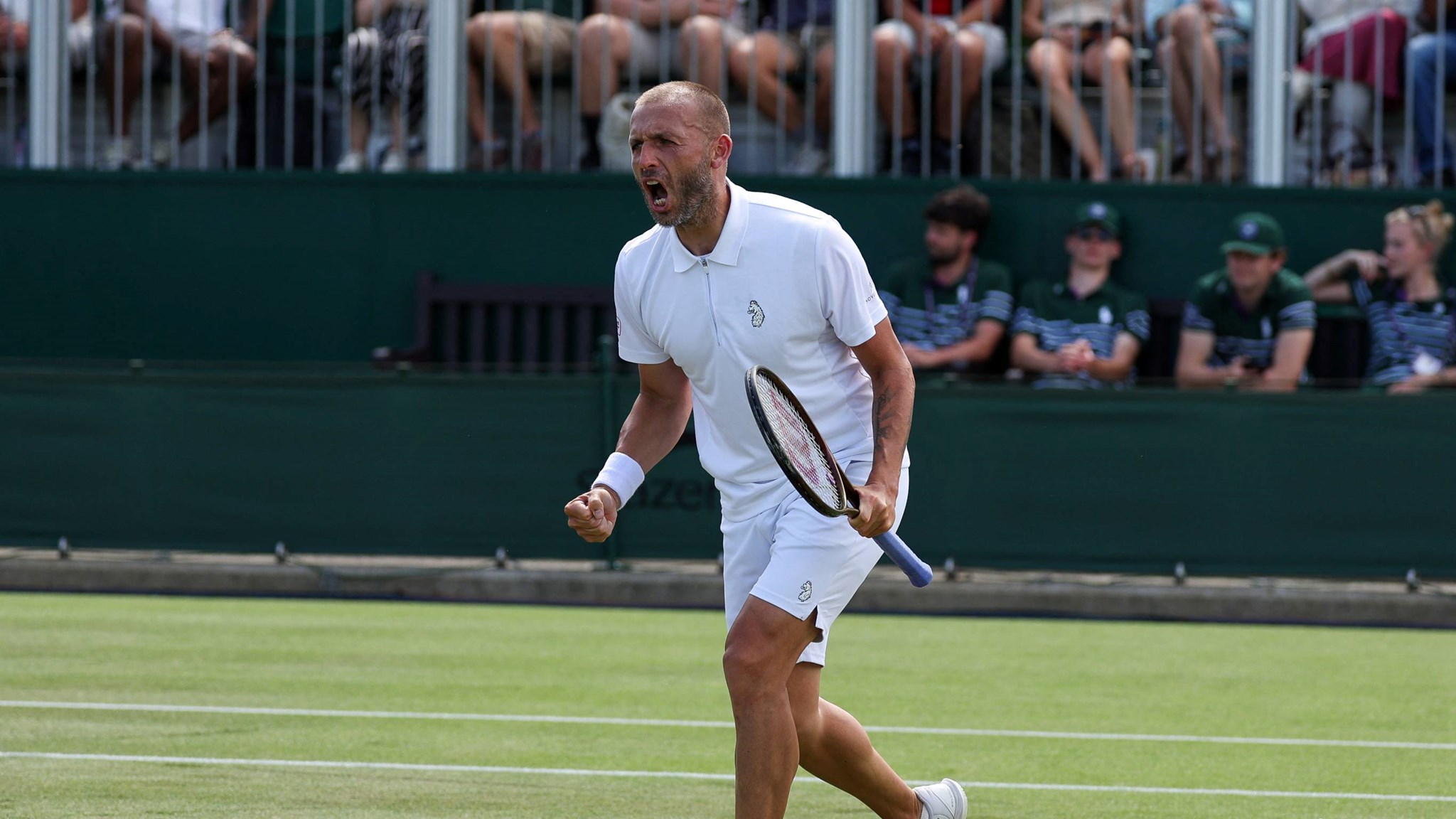 Dan Evans holding his tennis racket in his hand and screaming after winning a game at Wimbledon against fellow Brit Jay Clarke