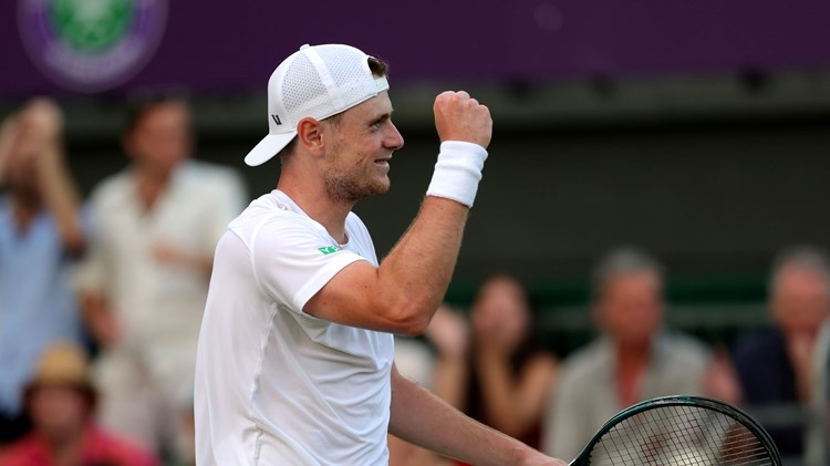 Jack Pinnington Jones smiling while holding his tennis racket after winning his first round match at Wimbledon