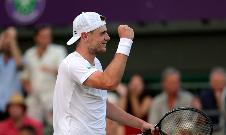 Jack Pinnington Jones smiling while holding his tennis racket after winning his first round match at Wimbledon