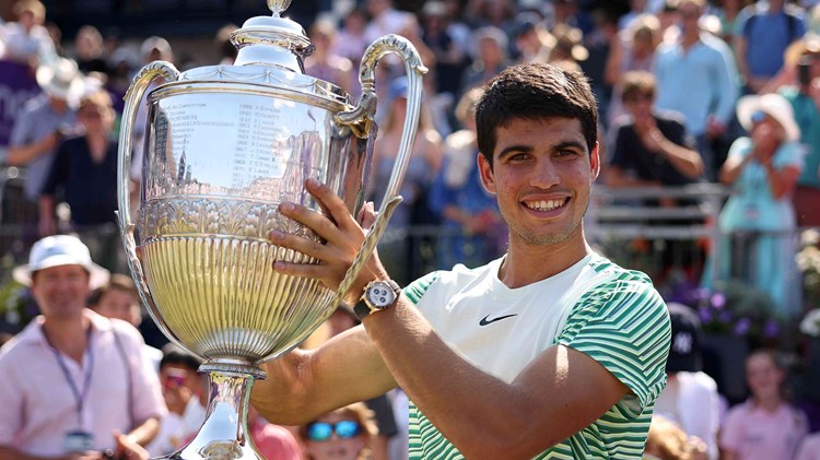 Carlos Alcaraz smiling on court while lifting the cinch Championships trophy