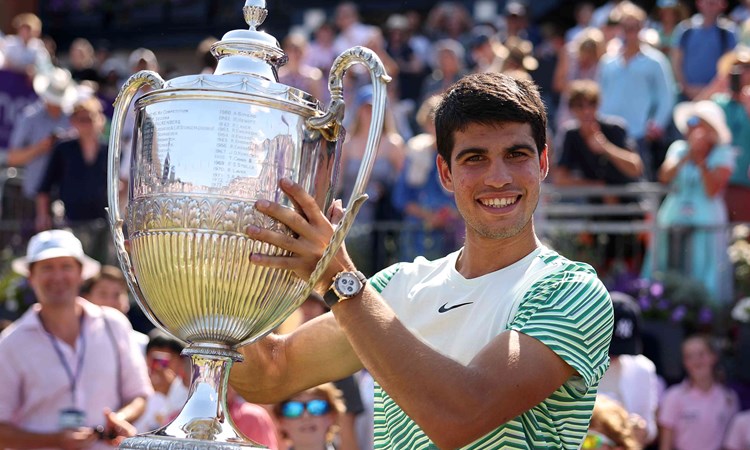 Carlos Alcaraz smiling on court while lifting the cinch Championships trophy