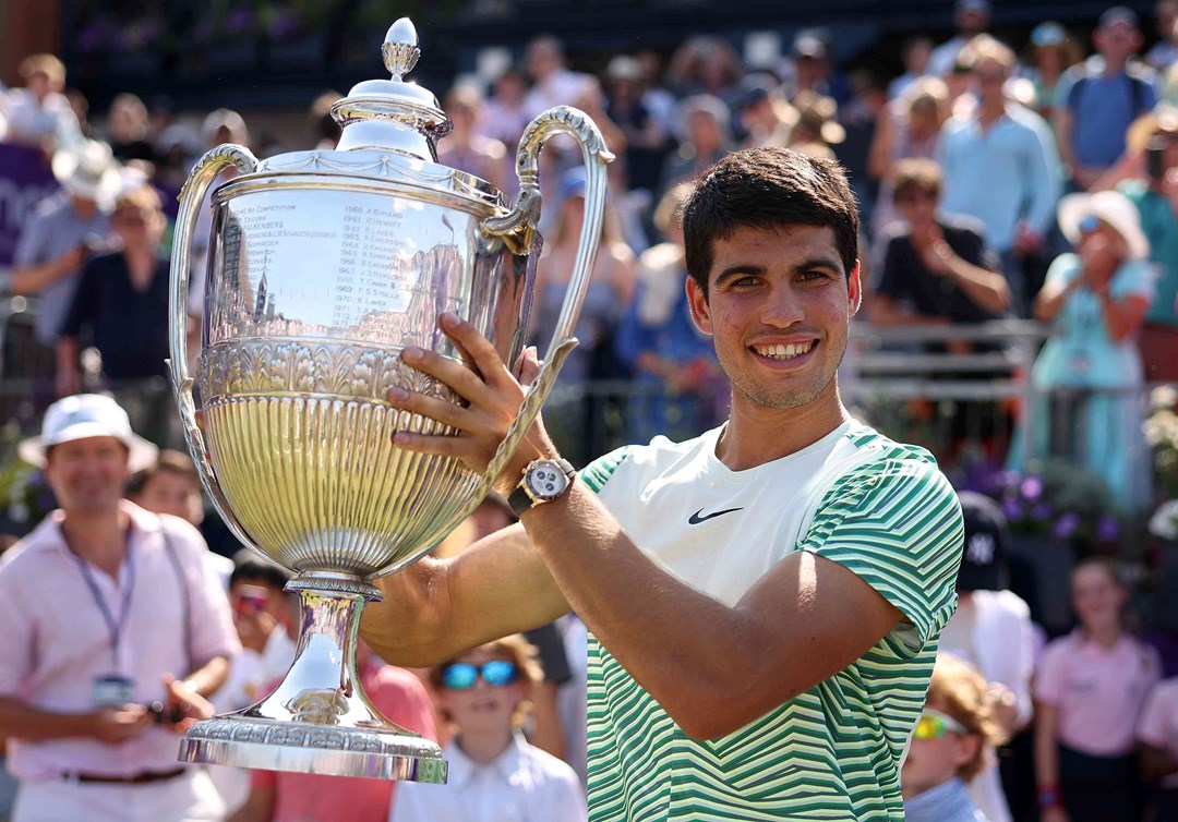 Carlos Alcaraz smiling on court while lifting the cinch Championships trophy