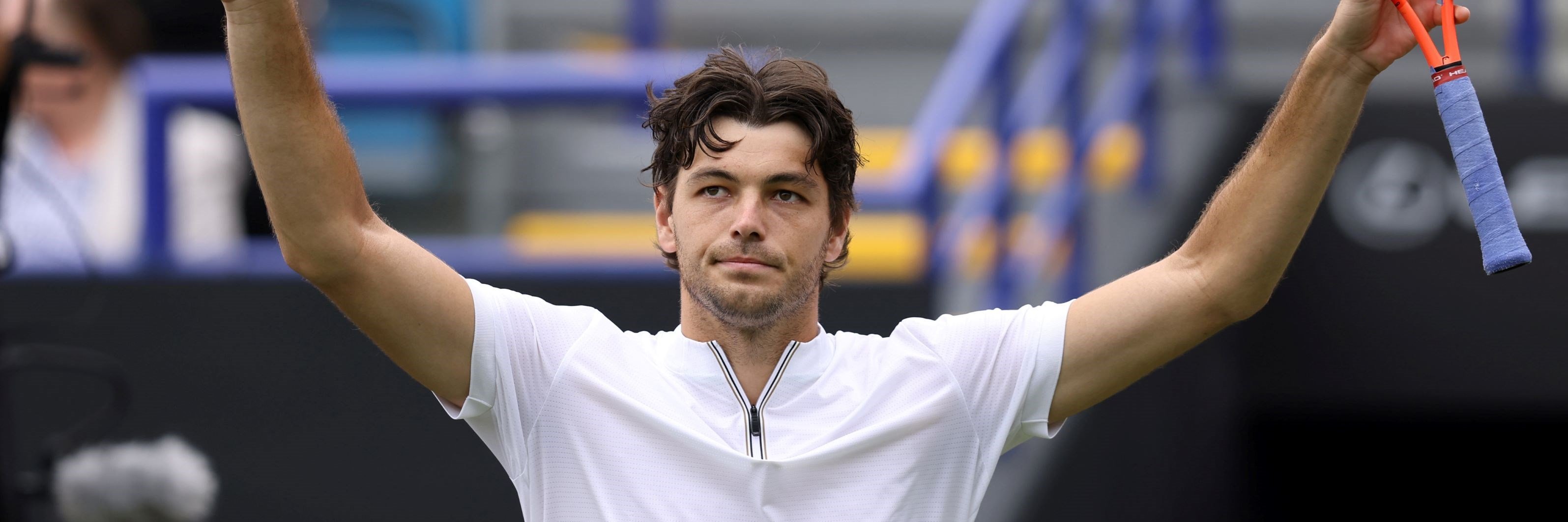 Taylor Fritz holding his hands up in the air and waving to fans on court at the Lexus Eastbourne Open