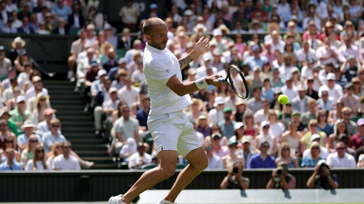 British tennis player Dan Evans hitting a forehand on Centre Court at Wimbledon during his second round match against Novak Djokovic 