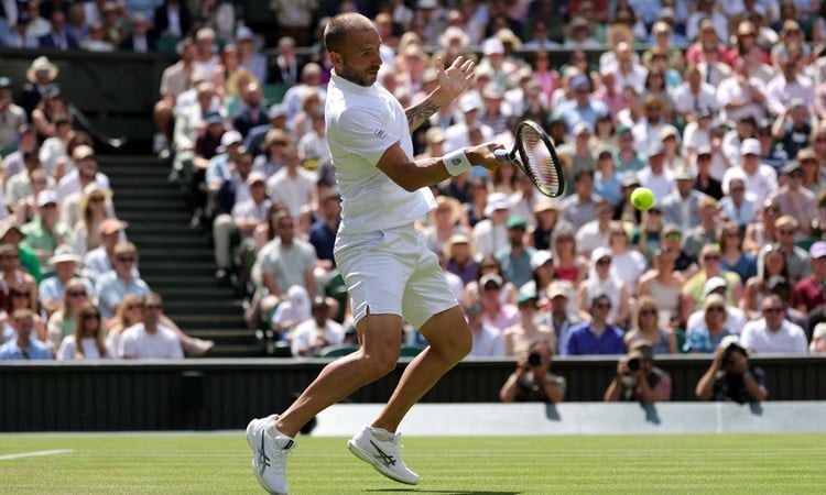 British tennis player Dan Evans hitting a forehand on Centre Court at Wimbledon during his second round match against Novak Djokovic 