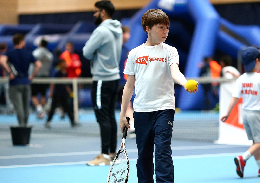 SERVES kid on court with a tennis ball