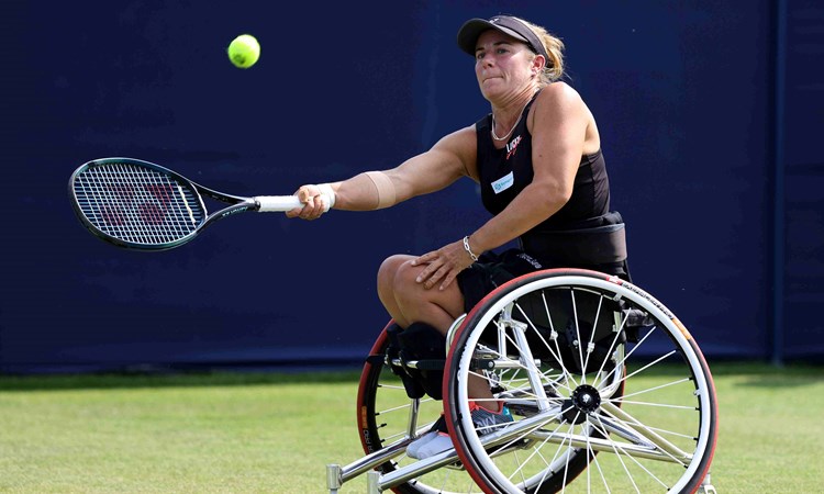 Lucy Shuker hitting a forehand while sat in her wheelchair on a grass court