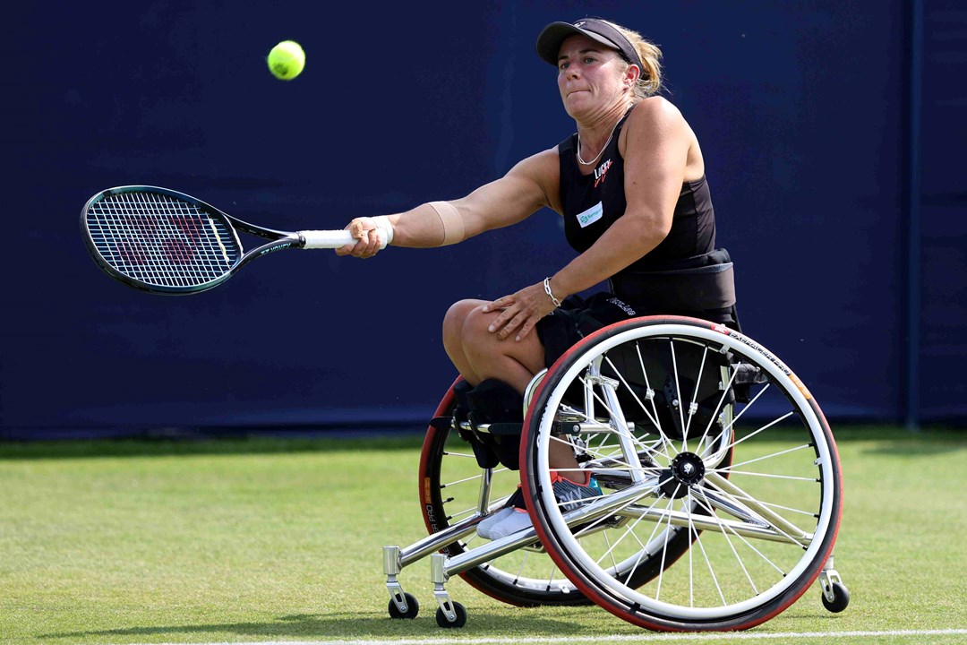 Lucy Shuker hitting a forehand while sat in her wheelchair on a grass court