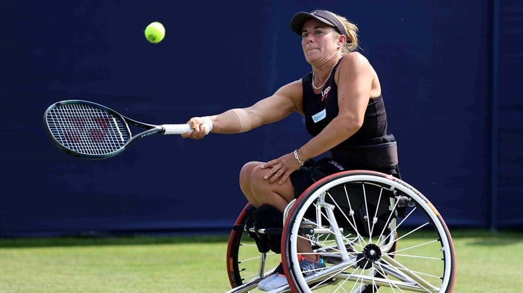 Lucy Shuker hitting a forehand while sat in her wheelchair on a grass court
