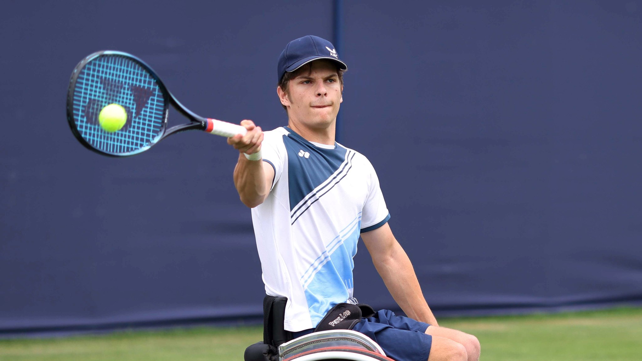 Greg Slade sat in his wheelchair hitting a forehand on a grass court 