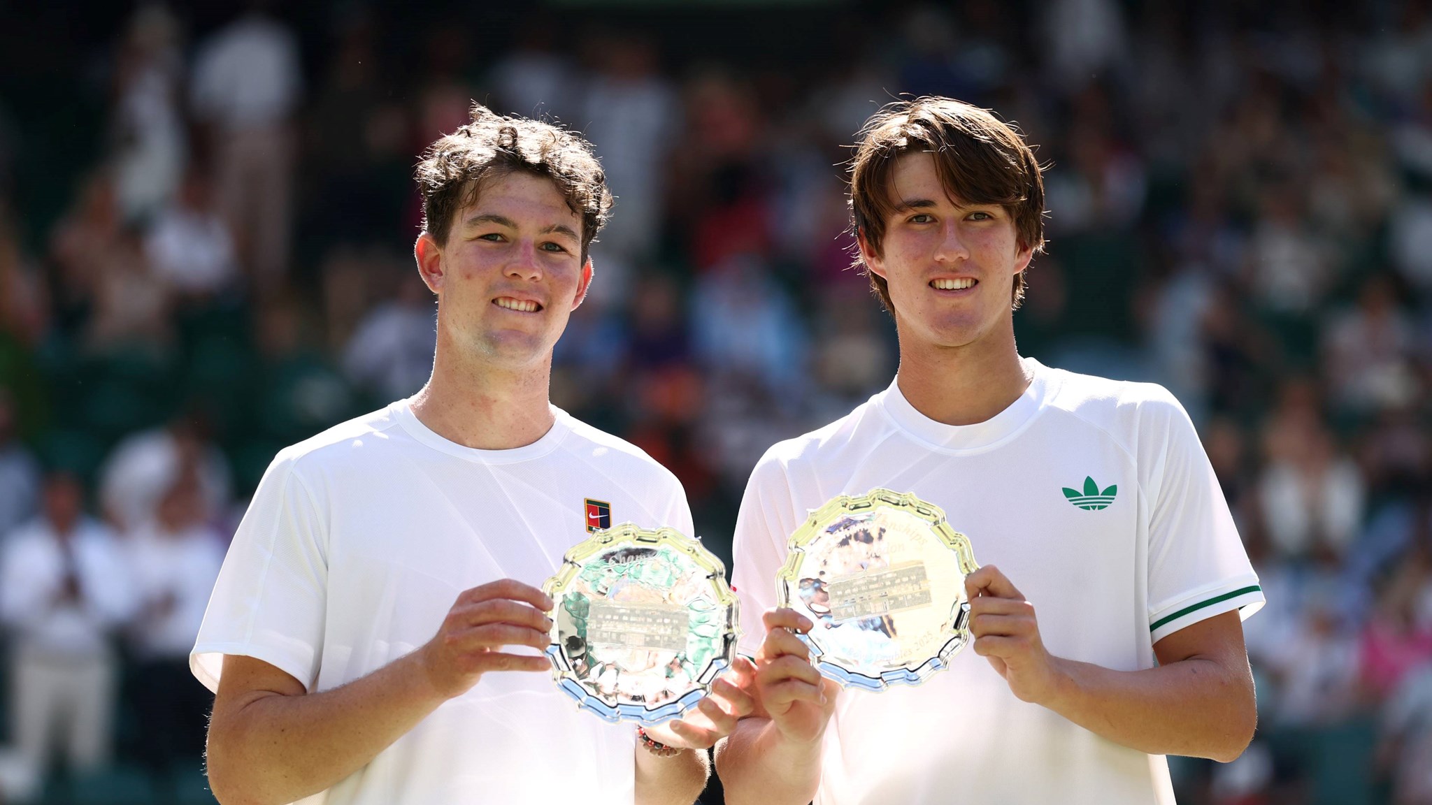 Oliver Bonding and Jagger Leach smile and hold up their boy's doubles runner-up trophy at Wimbledon