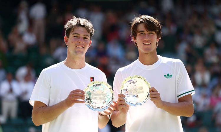 Oliver Bonding and Jagger Leach smile and hold up their boy's doubles runner-up trophy at Wimbledon