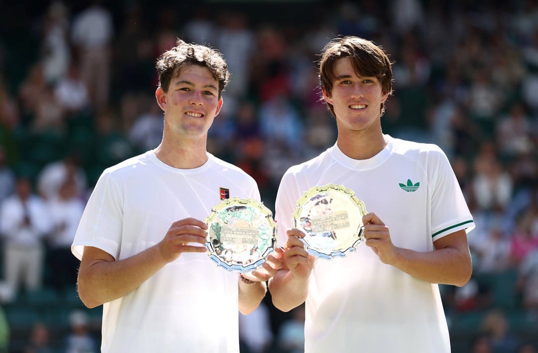 Oliver Bonding and Jagger Leach smile and hold up their boy's doubles runner-up trophy at Wimbledon