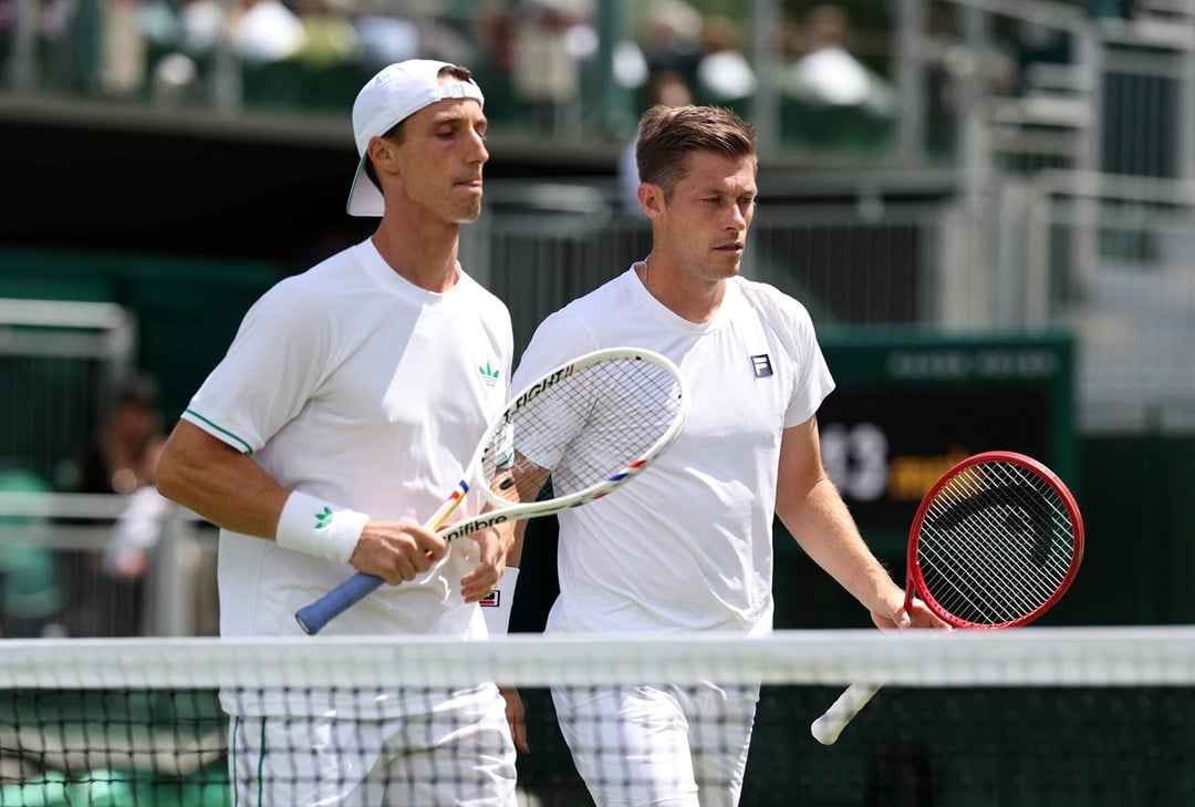 Joe Salisbury and Neal Skupkski walk towards the net with their rackets in hand