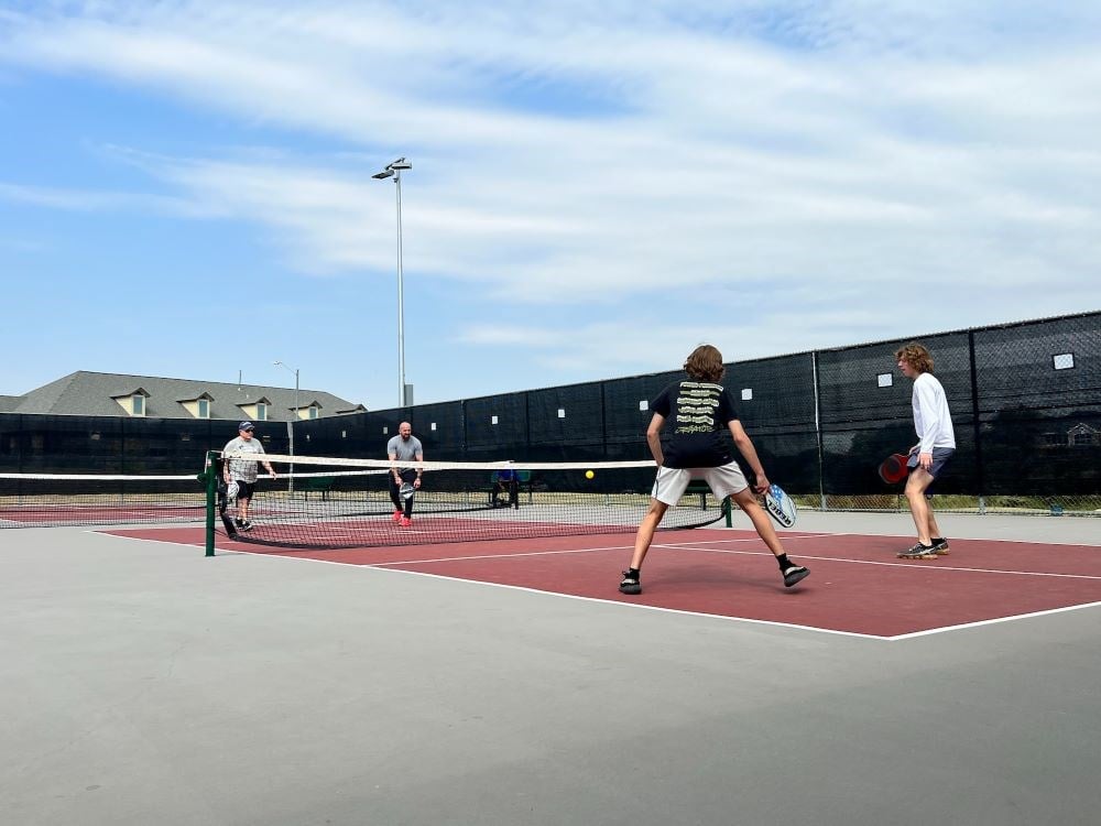 4 players playing pickleball outside on a court