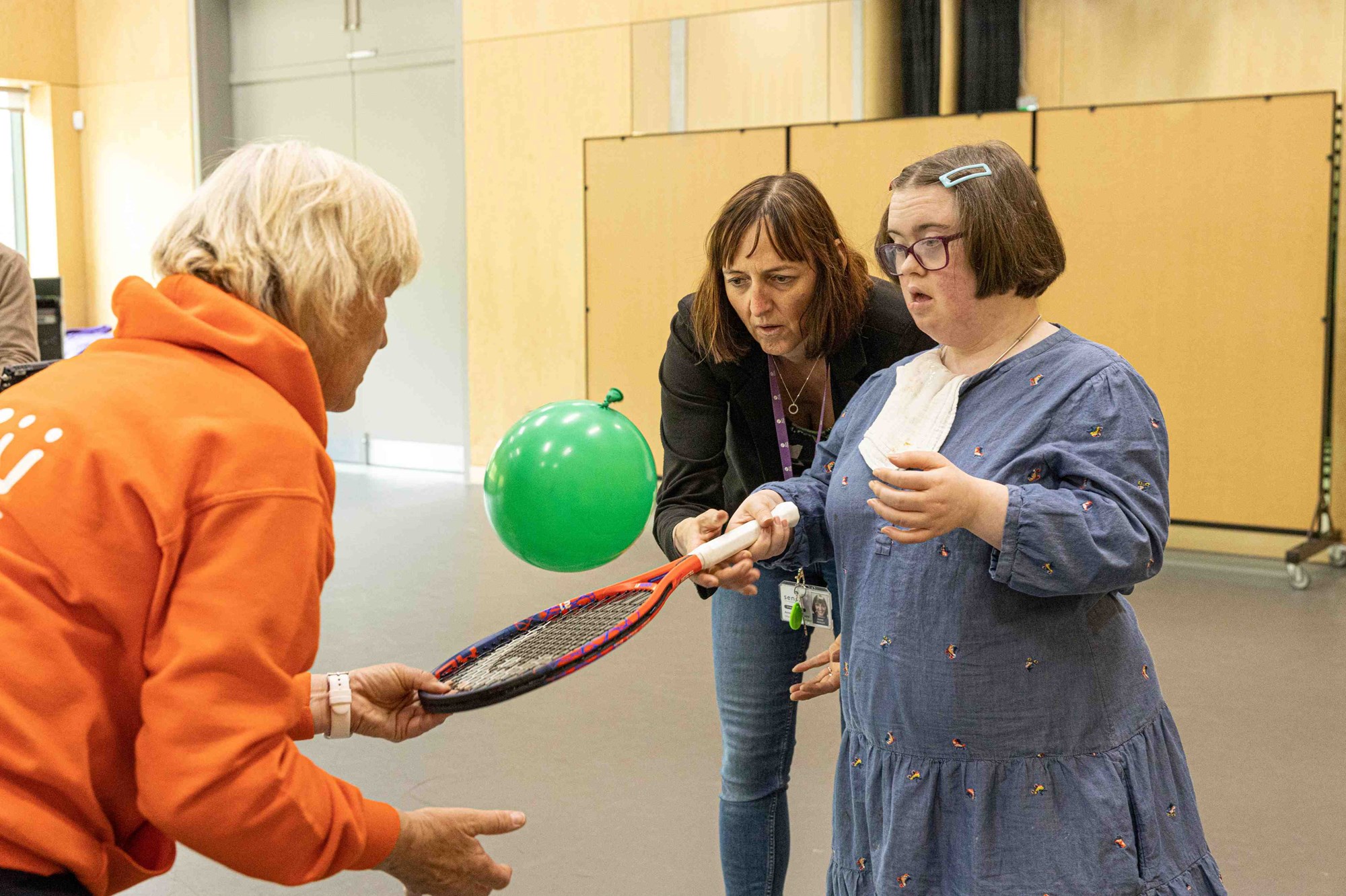 A woman hitting a balloon with a tennis racket.