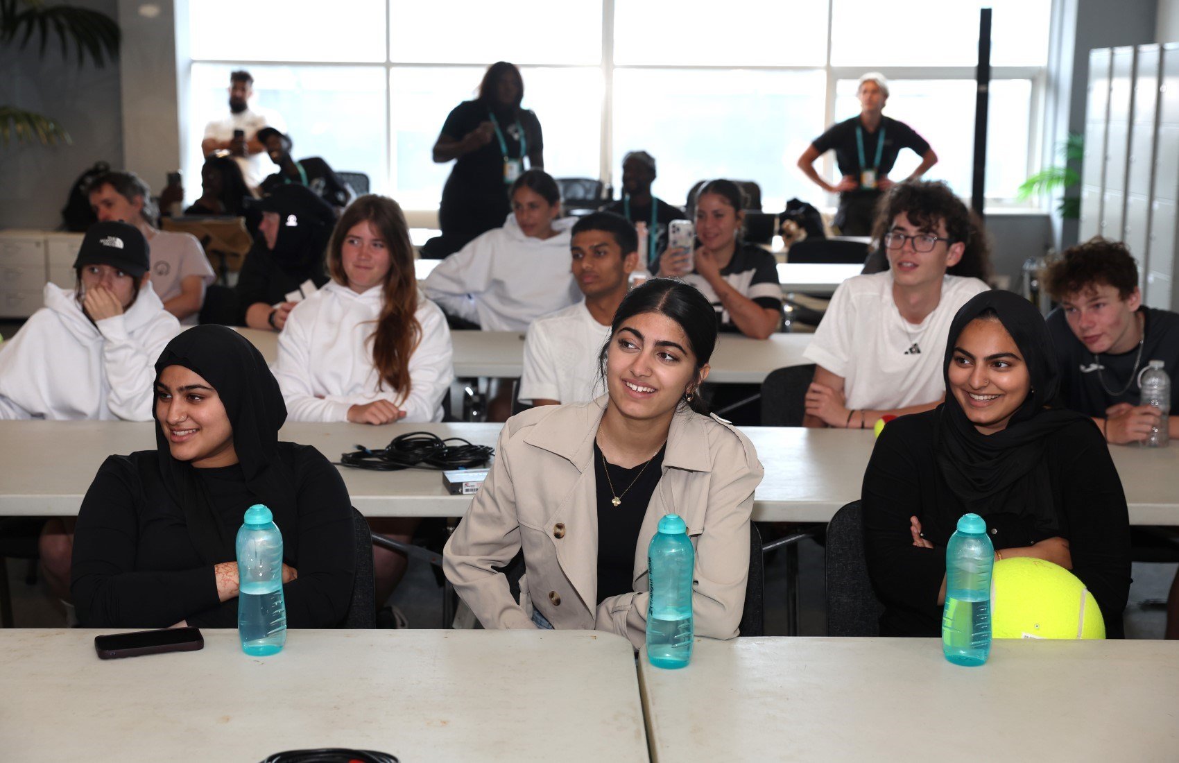 Group of young people sit at row of tables listening 