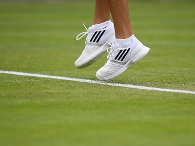 Shot of a person's shoes mid-jump on a tennis court
