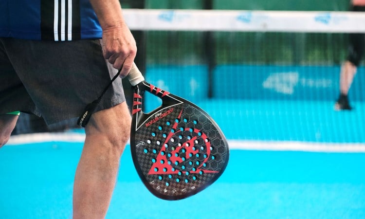 A padel bat being held by a man standing on a padel court