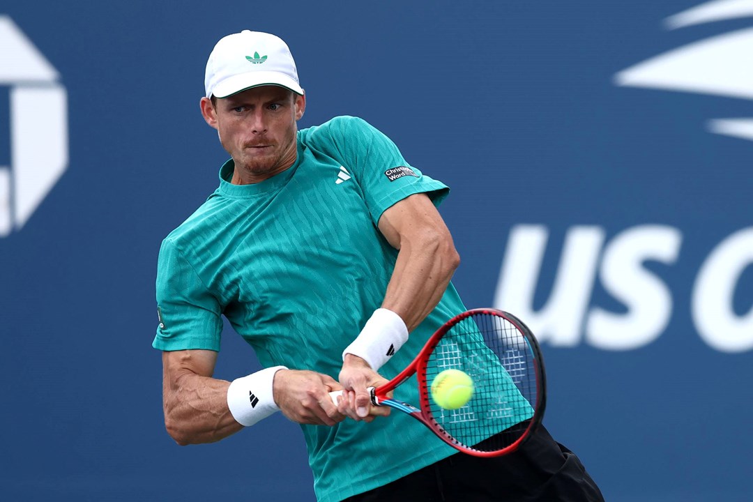 British tennis player Billy Harris wearing a teal Adidas top and hitting a backhand on court at the US Open