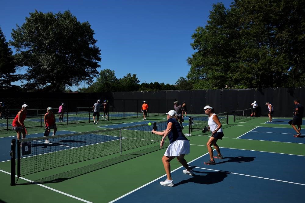A park full of pickleball courts being used by several players