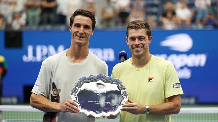 British tennis players Joe Salisbury and Neal Skupski holding their US Open men's doubles runner-up trophy on court