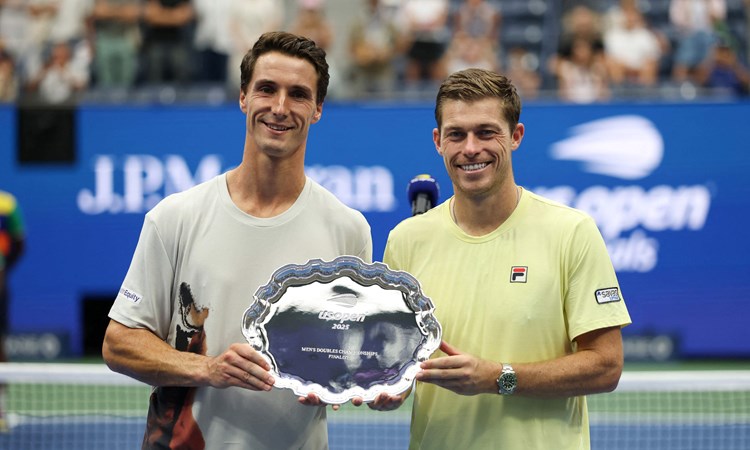 British tennis players Joe Salisbury and Neal Skupski holding their US Open men's doubles runner-up trophy on court