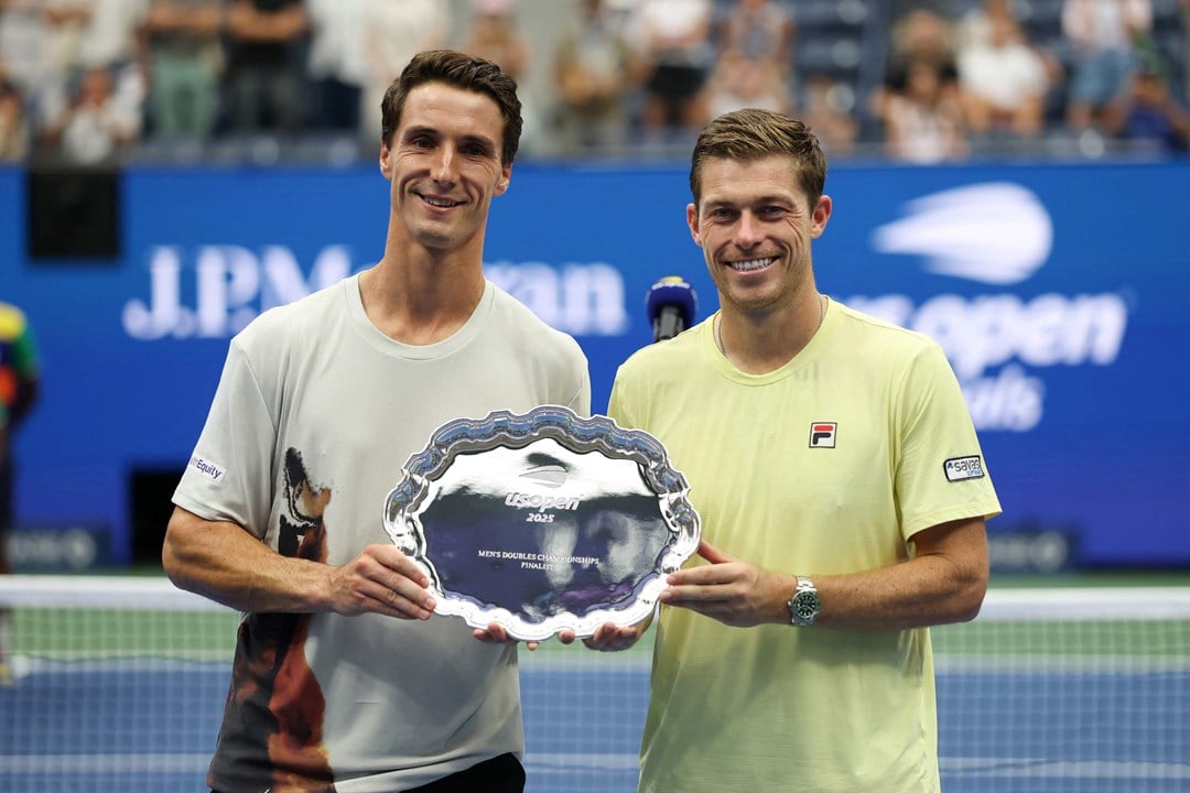 British tennis players Joe Salisbury and Neal Skupski holding their US Open men's doubles runner-up trophy on court