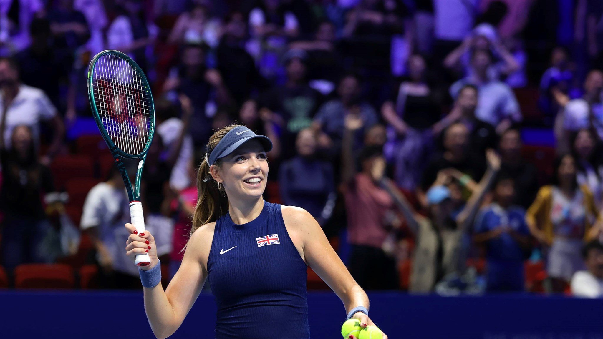 British tennis player Katie Boulter smiling while holding her racket in the air at the Billie Jean King Cup Finals in Shenzhen