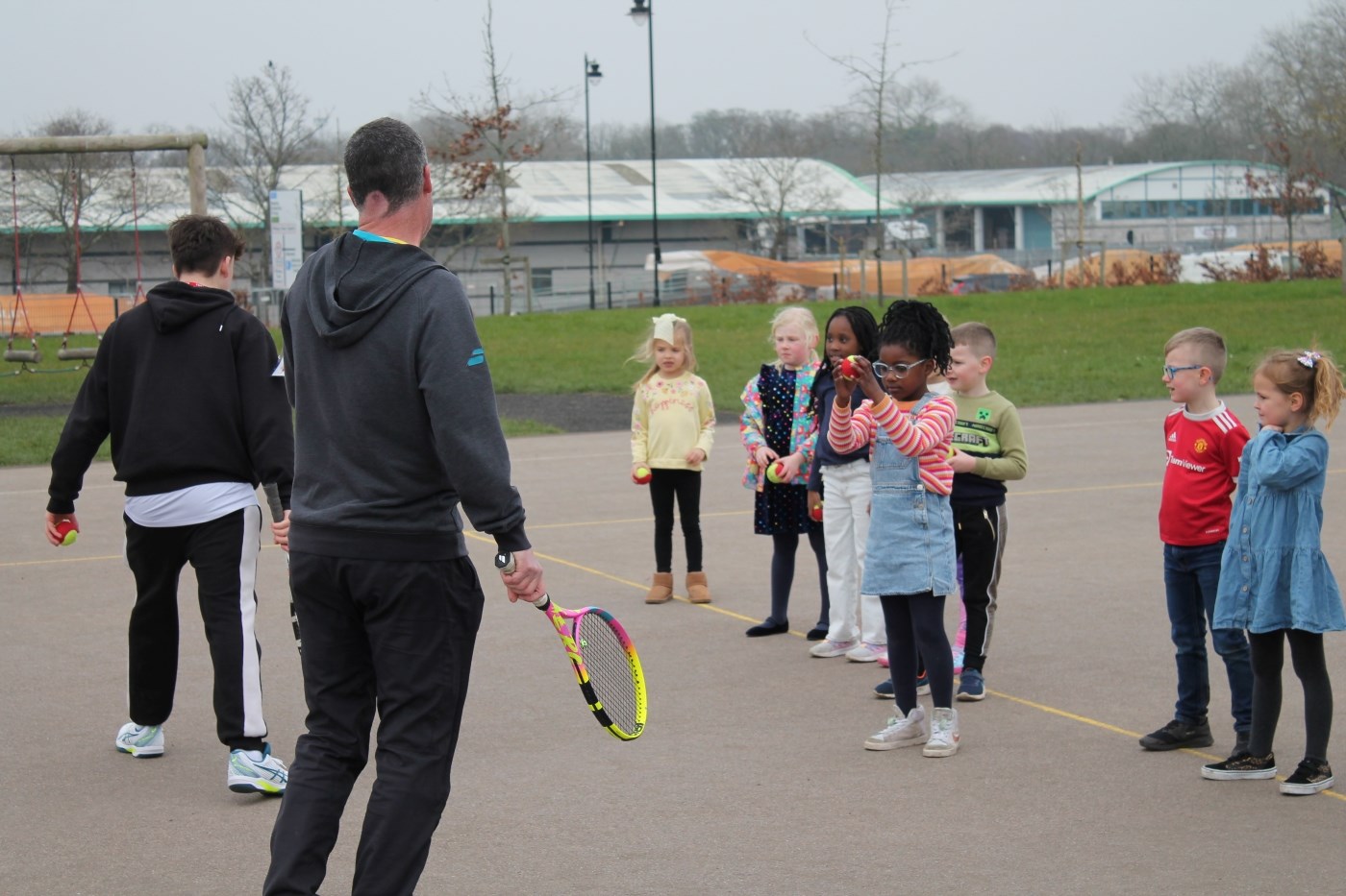 Primary school student taking part in tennis skills with a tennis coach