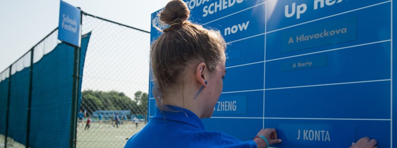 A tennis volunteer changing the scoreboard