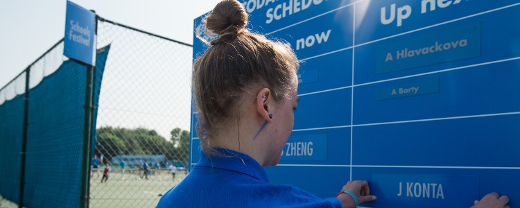 A tennis volunteer changing the scoreboard