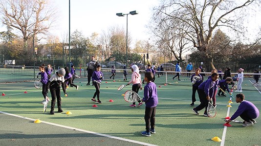 kids taking part in a community tennis session on park tennis courts