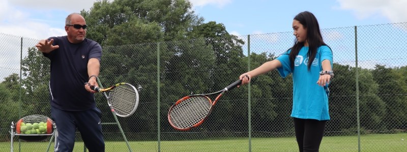 Jonty Solomons coaching a young girl at a local tennis court