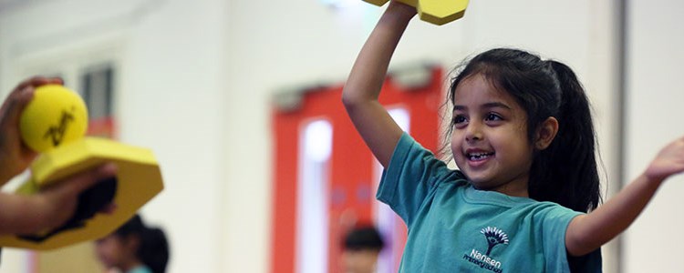 A young girl enjoying a tennis based game at school