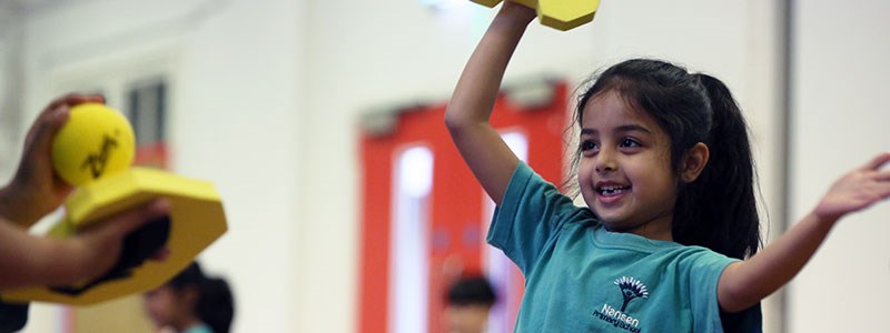 A young girl enjoying a tennis based game at school