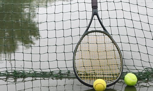 Tennis racket against net on wet tennis court