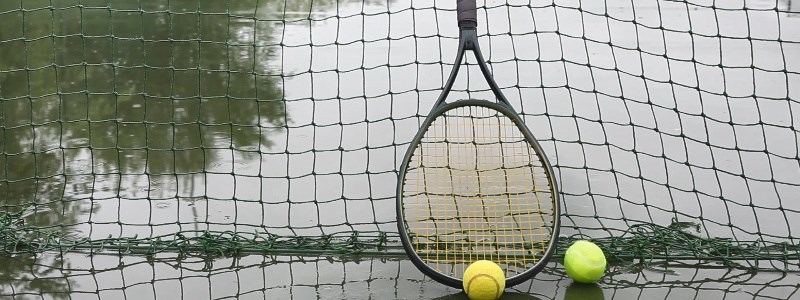 Tennis racket against net on wet tennis court