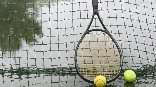 Tennis racket against net on wet tennis court