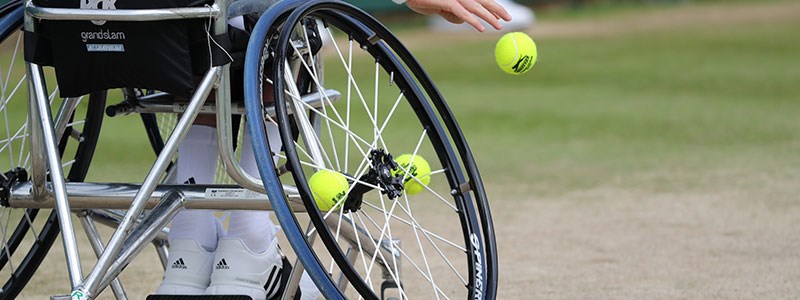 Wheelchair and tennis balls on grass