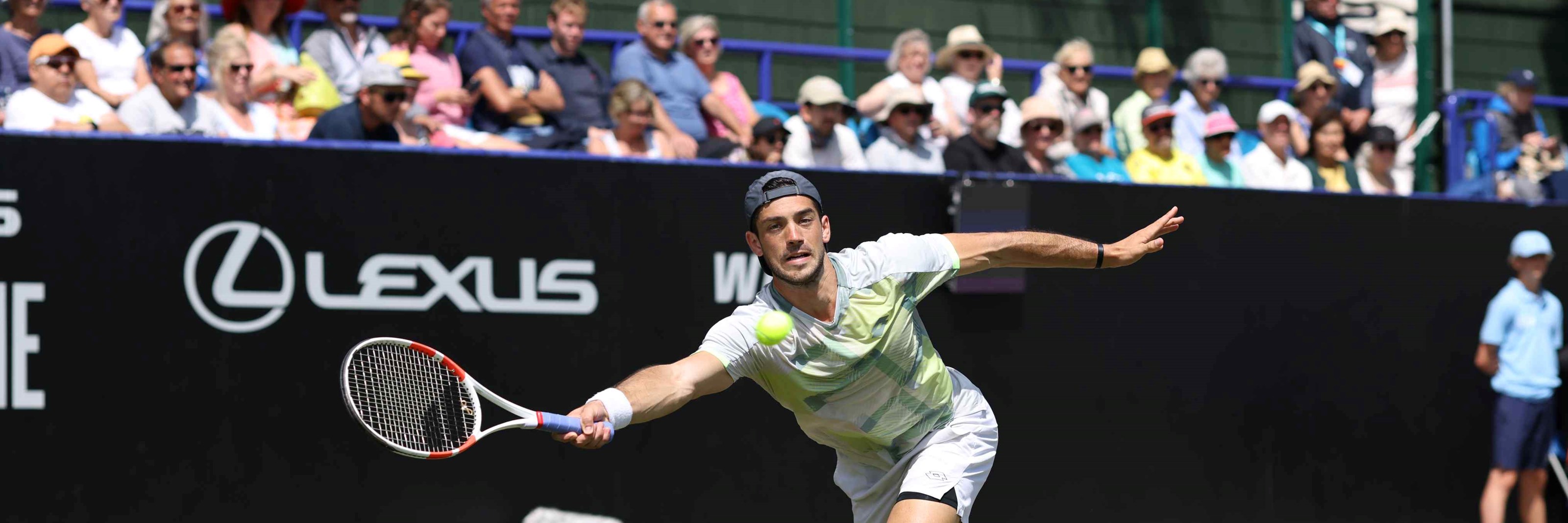 Julian Cash reaching to hit a forehand on court at the Lexus Eastbourne Open