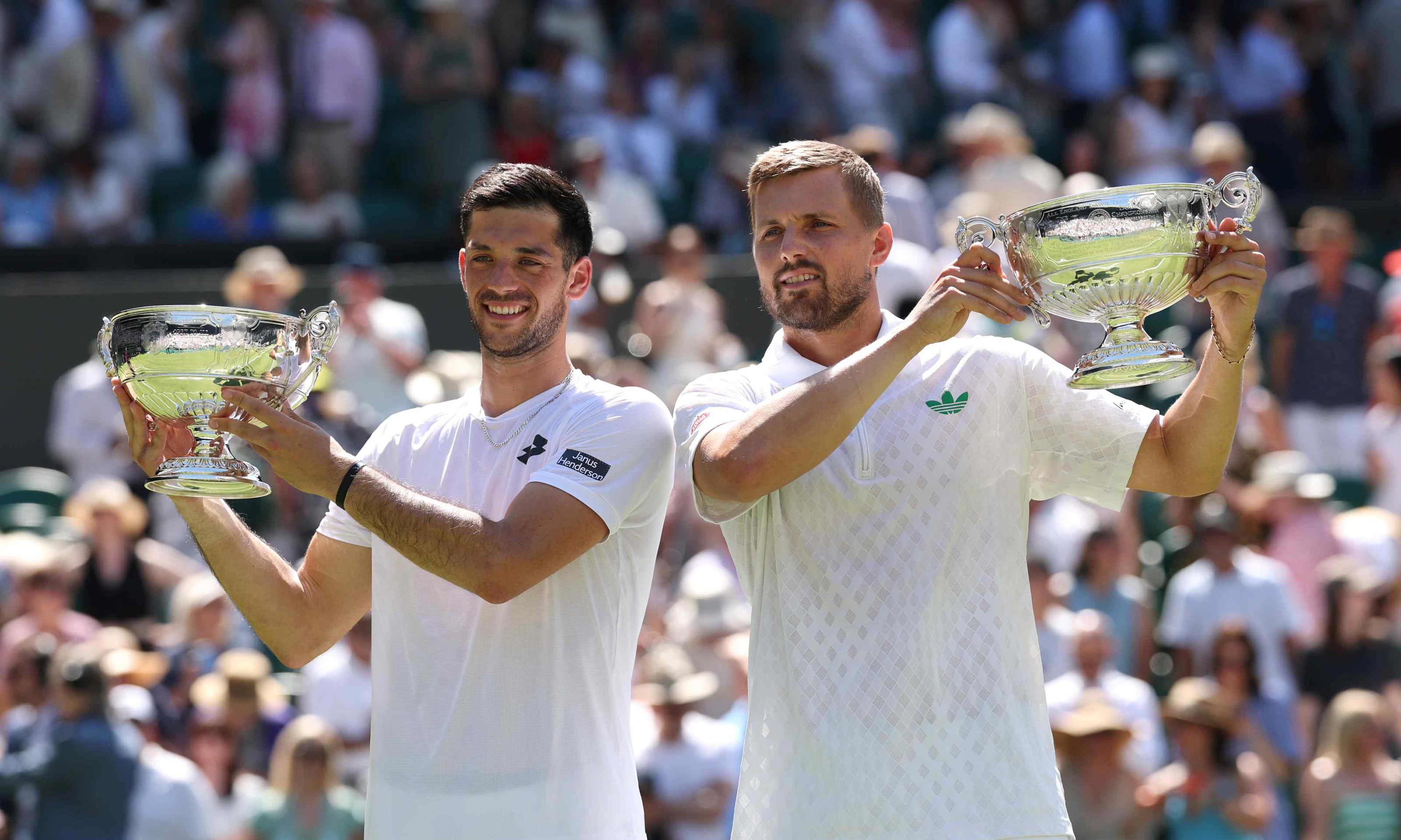 British doubles duo Julian Cash and Lloyd Glasspool smiling while holding their men's doubles Wimbledon title