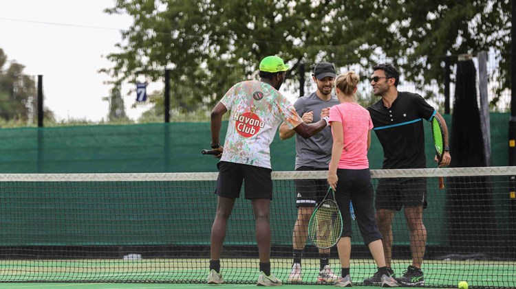 Four people shaking hands on a tennis court at the net