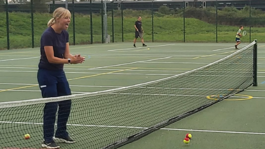 Kari Davies coaching a child on a tennis court