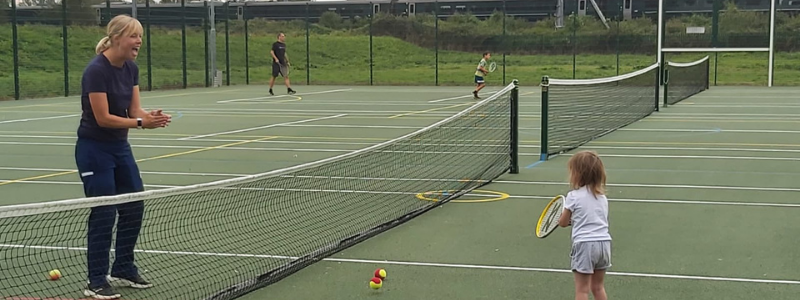 Kari Davies coaching a child on a tennis court