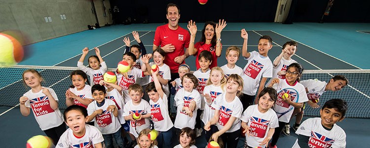 Large group of kids with tennis balls on a tennis court
