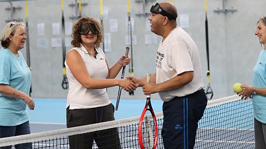 Two visually impaired players shake hands at the net