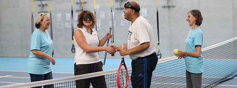 Two visually impaired players shake hands at the net