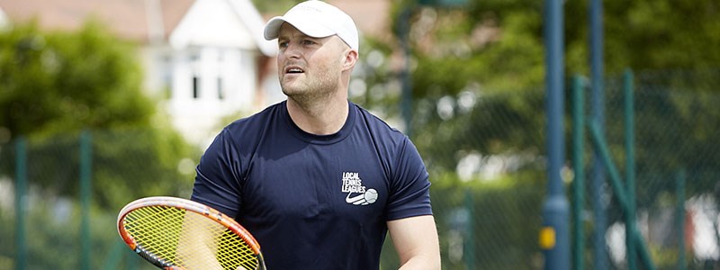 Man who works for Local Tennis Leagues holding a tennis racket